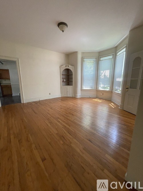 A room with wooden flooring and a window with blinds.
