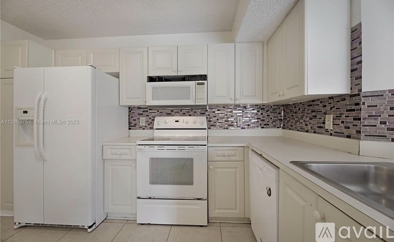 A kitchen with white appliances and cabinets.