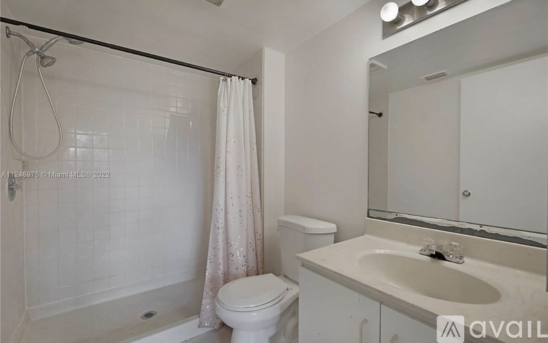 A white bathroom with a toilet, sink, and shower.