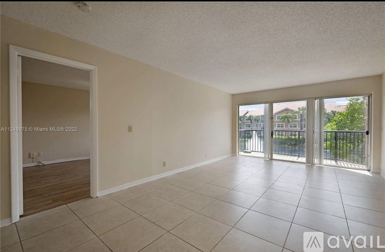 A spacious room with tiled flooring and sliding glass doors leading to a balcony.