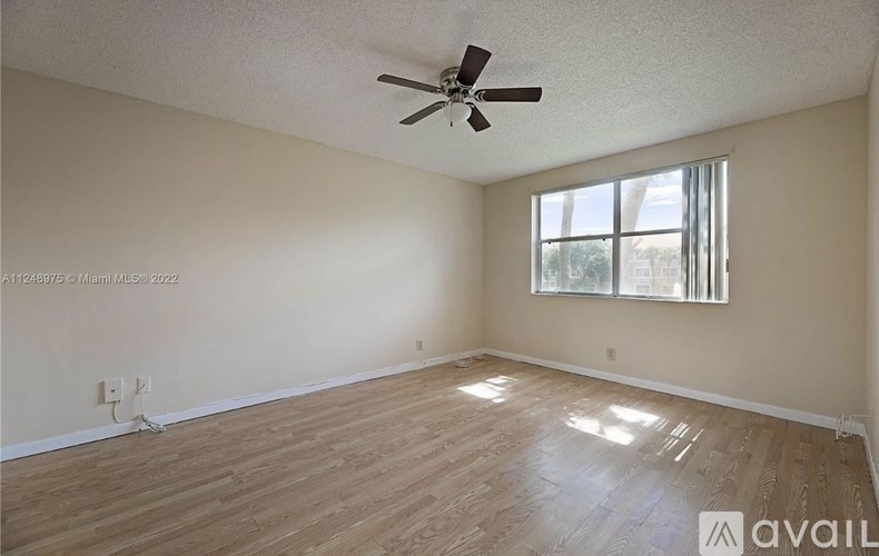 A room with a ceiling fan and wooden flooring.