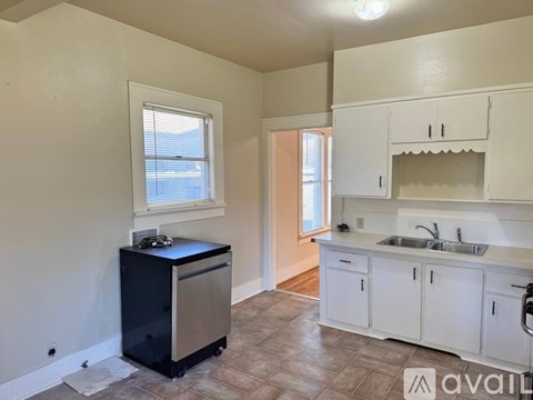 A kitchen with white cabinets and a black dishwasher.