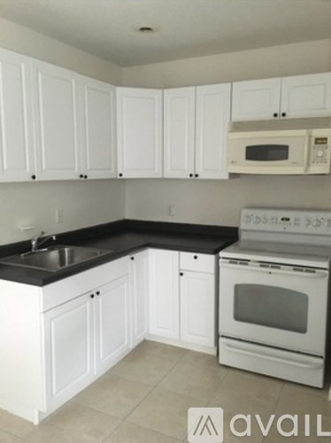 A kitchen with white cabinets and black countertops.
