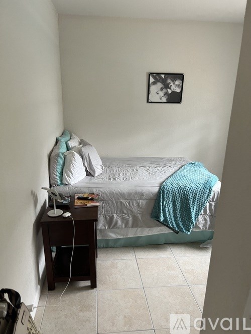 A small bedroom with a bed, a nightstand, and a picture on the wall.