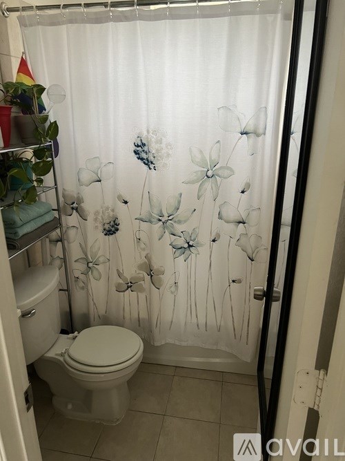 A bathroom with a toilet and a shower curtain with a flower design.