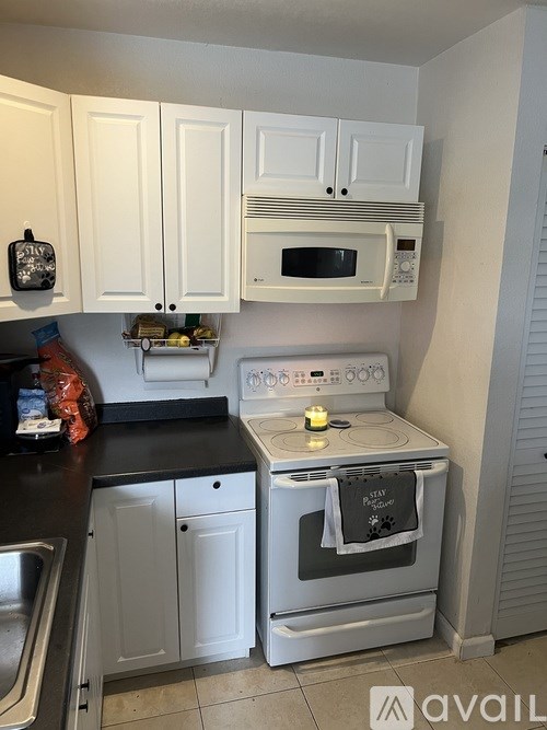A kitchen with white cabinets and a black countertop.