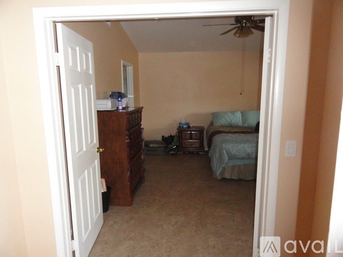 A room with a bed, dresser, and ceiling fan.