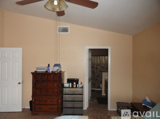 A room with a ceiling fan and a wooden chest of drawers.