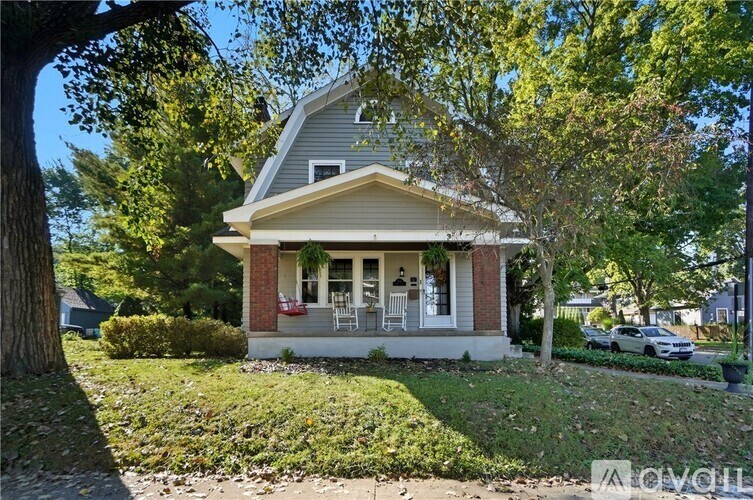 A house with a porch and a tree in front of it.