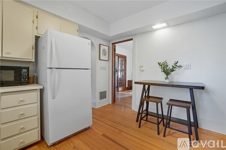 A white refrigerator is in a kitchen with wooden floors.