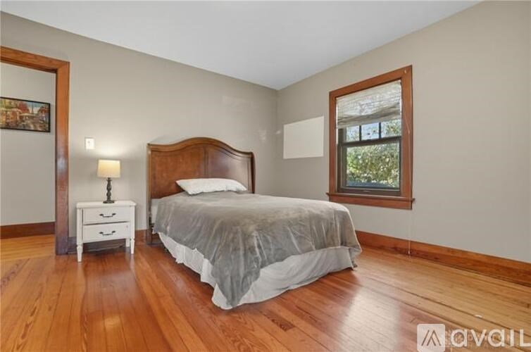 A bedroom with a bed, nightstand, and window.