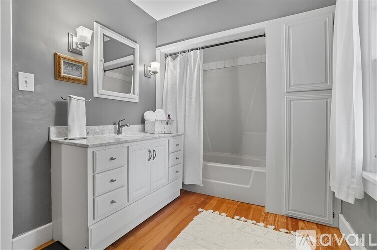 A white bathroom with a mirror, sink, and shower.