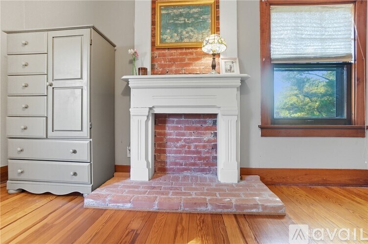 A white fireplace with a brick base and a painting above it.