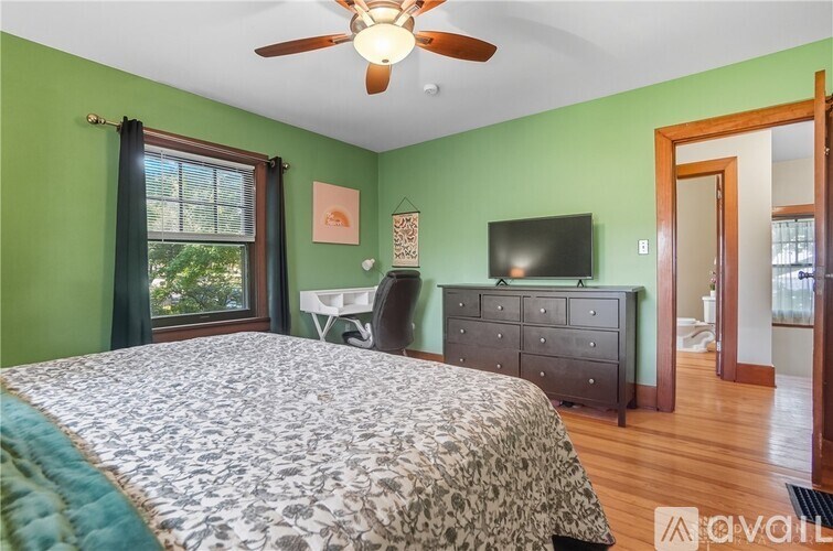 A bedroom with a bed, dresser, and television.