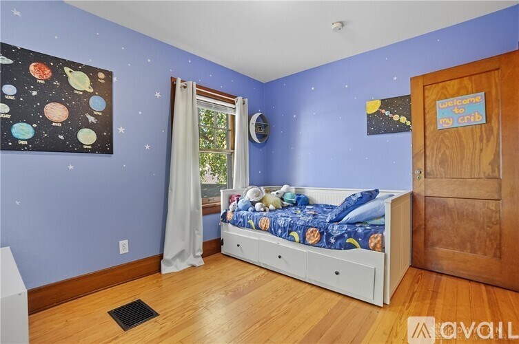 A child's bedroom with a white bed and a painting of planets on the wall.