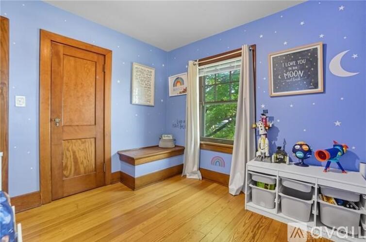 A room with blue walls and wooden floors, decorated with toys and a chalkboard.