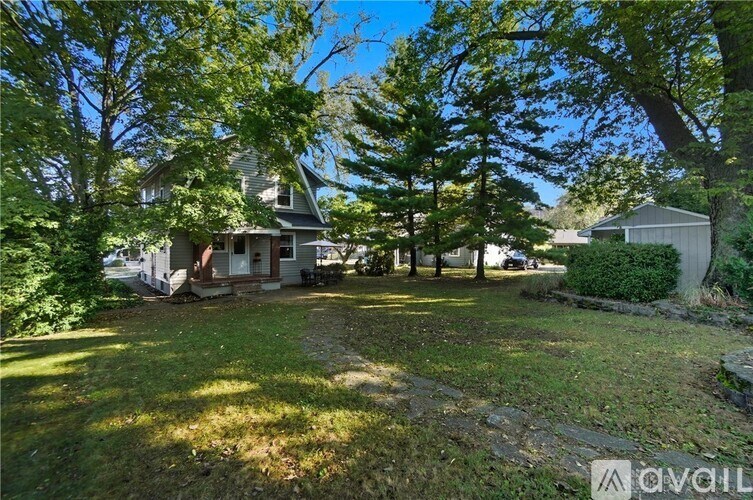 A house with a grey roof and a tree in front of it.