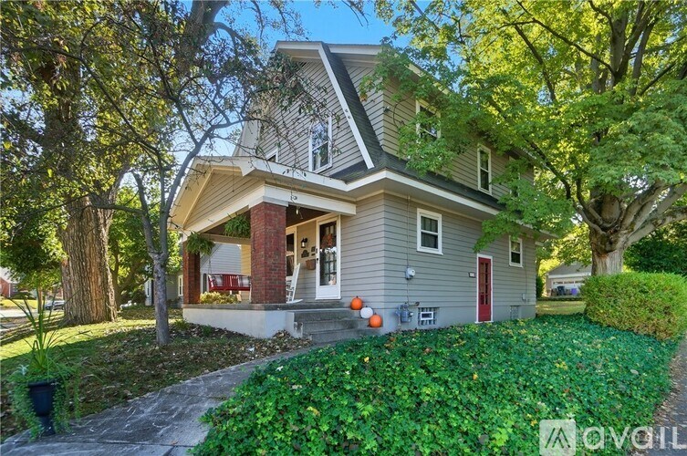 A house with a red door and a porch with a few pumpkins on it.