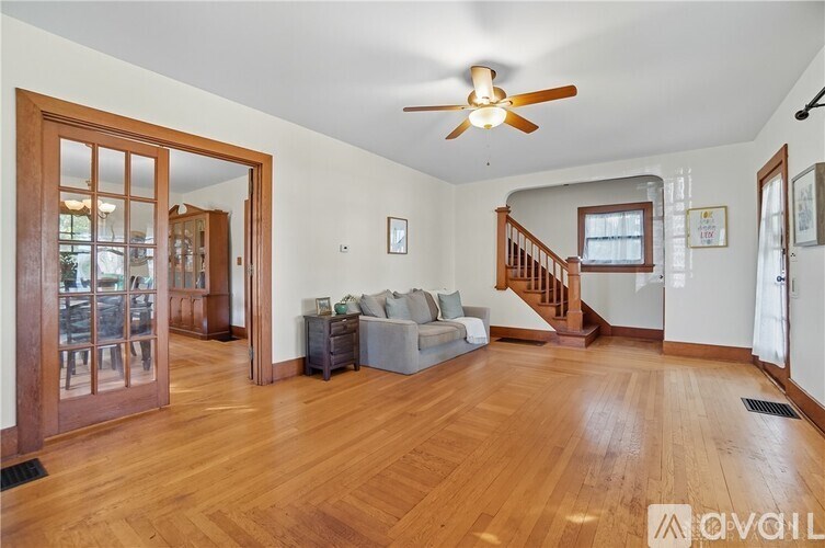 A living room with a couch, a ceiling fan, and a staircase.