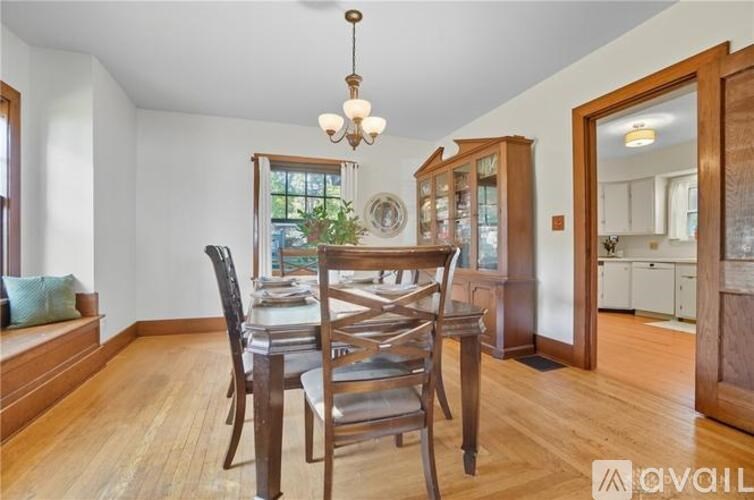A wooden dining table with chairs and a chandelier hangs in a room.
