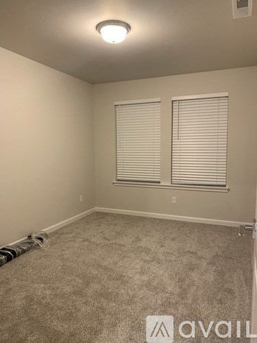 A room with beige carpet and a window with blinds.