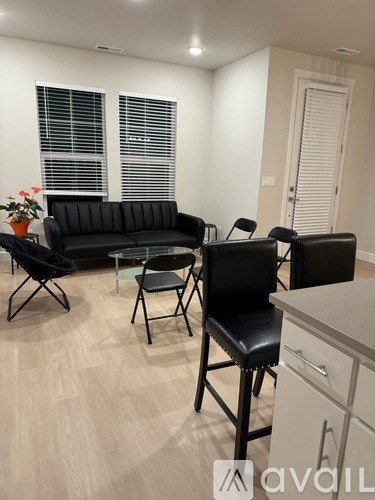 A living room with a black sofa, two chairs, and a table.