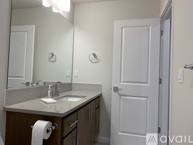 A bathroom with a sink, mirror, and toilet paper roll.