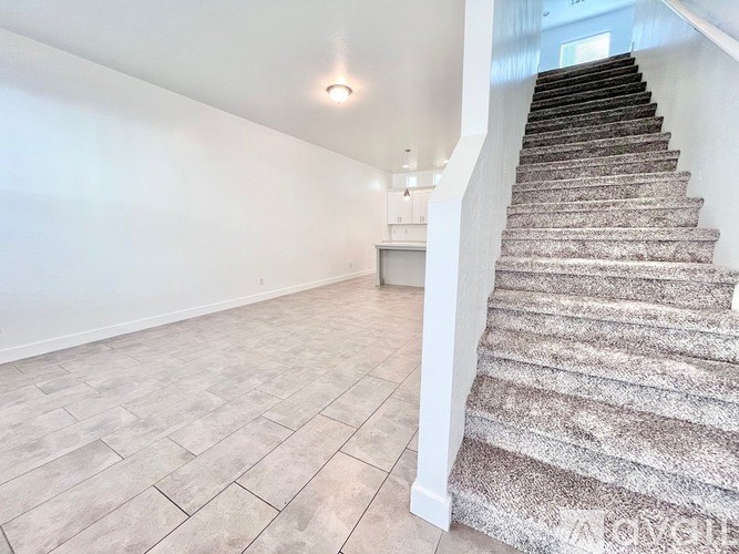 A staircase with a carpeted runner and wooden steps leads up to a brightly lit landing.