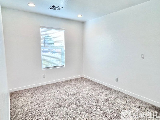A room with a carpeted floor and a window with blinds.