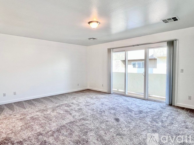 A room with a carpeted floor and a sliding glass door.