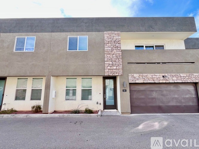 A modern two-story house with a garage door and a stone pillar.
