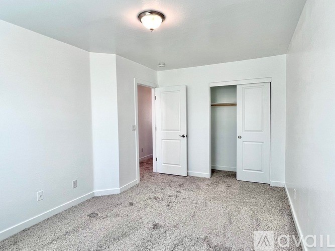 A room with a carpeted floor and two doors.