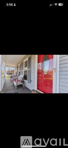 A red door is on the right side of a white house.
