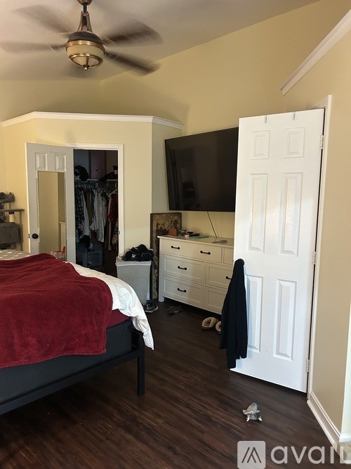 A bedroom with a bed, dresser, and a ceiling fan.