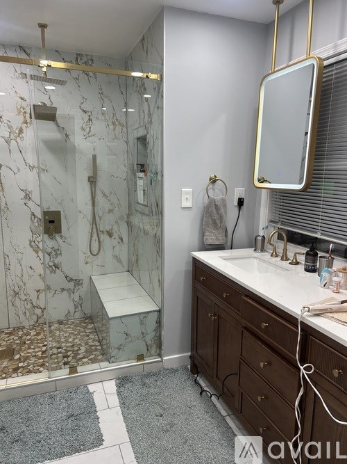 A bathroom with a marble shower and a white sink.