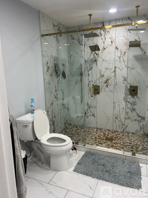A bathroom with a marble wall and a glass shower.