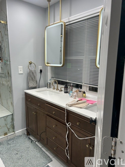 A bathroom with a marble shower and a vanity with a gold framed mirror.