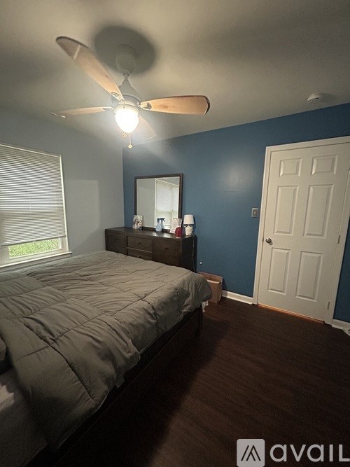 A bedroom with a bed, dresser, mirror, and a ceiling fan.