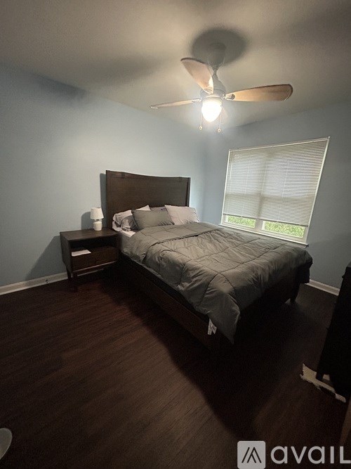A bedroom with a bed, nightstand, and window.