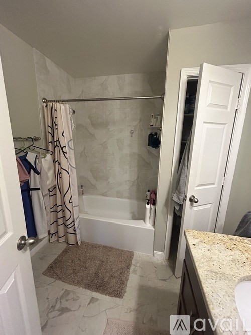A bathroom with a shower curtain and a rug on the floor.