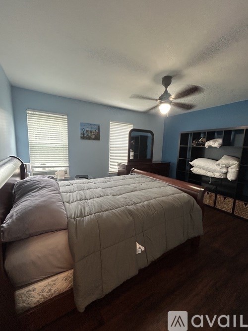 A bedroom with a bed, a ceiling fan, and a nightstand.