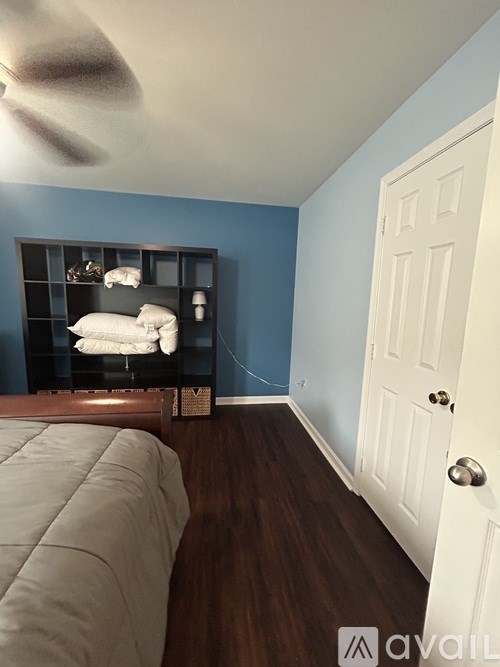 A room with a bed and a shelf with pillows on it.