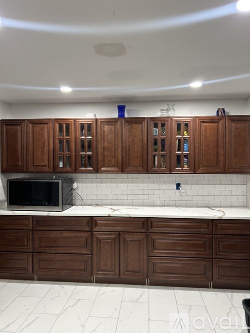 A kitchen with brown cabinets and a black microwave.