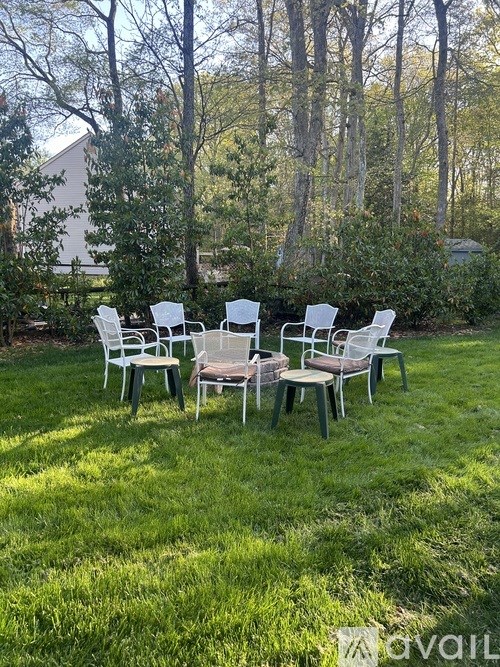 A set of white chairs are arranged on a lawn.
