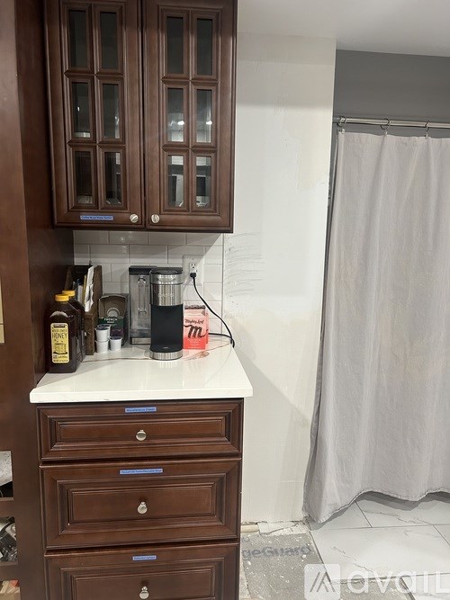 Brown cabinets above a counter with a bottle on it.
