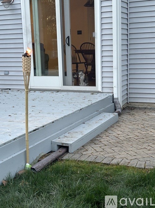 A dog is sitting on a porch with a pole in the foreground.