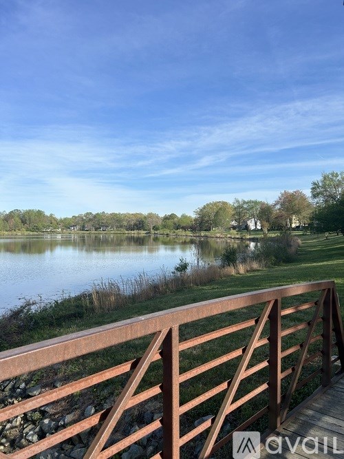 A wooden bridge over a calm lake with a clear blue sky.