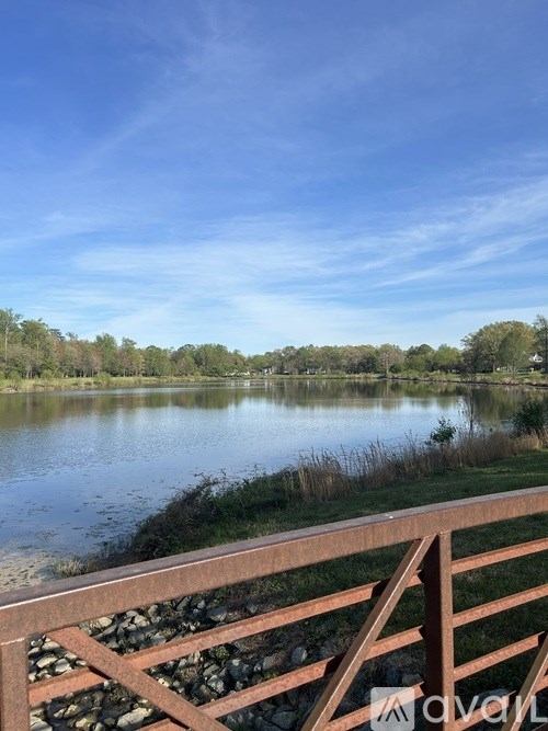 A serene lake surrounded by trees under a clear blue sky.