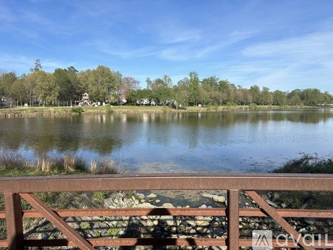 A serene lake surrounded by trees and a clear sky.
