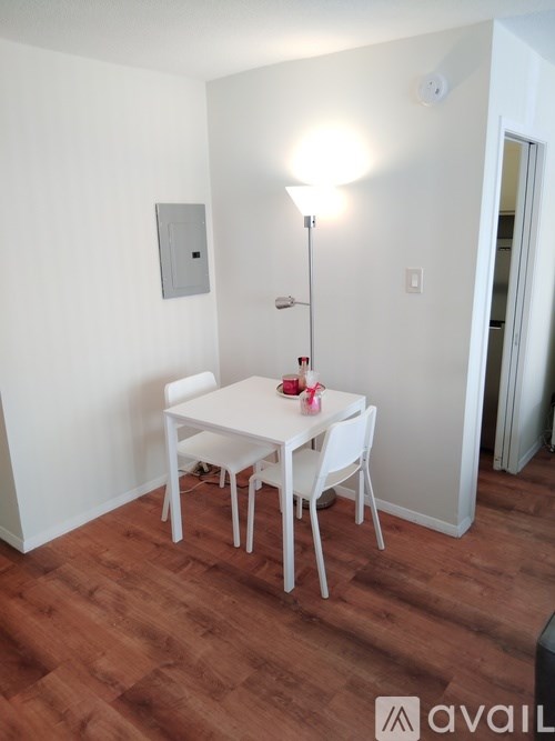 A small white table with four chairs is in a room with wooden floors.
